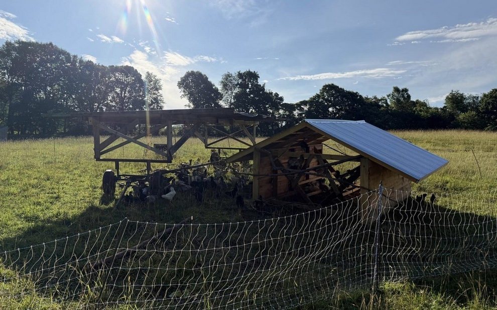 A homemade shade shelter on running gear and an open air chicken coop on skids at The Wildwoods Farm